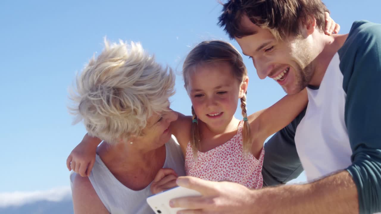 Multi generation family using mobile phone at beach