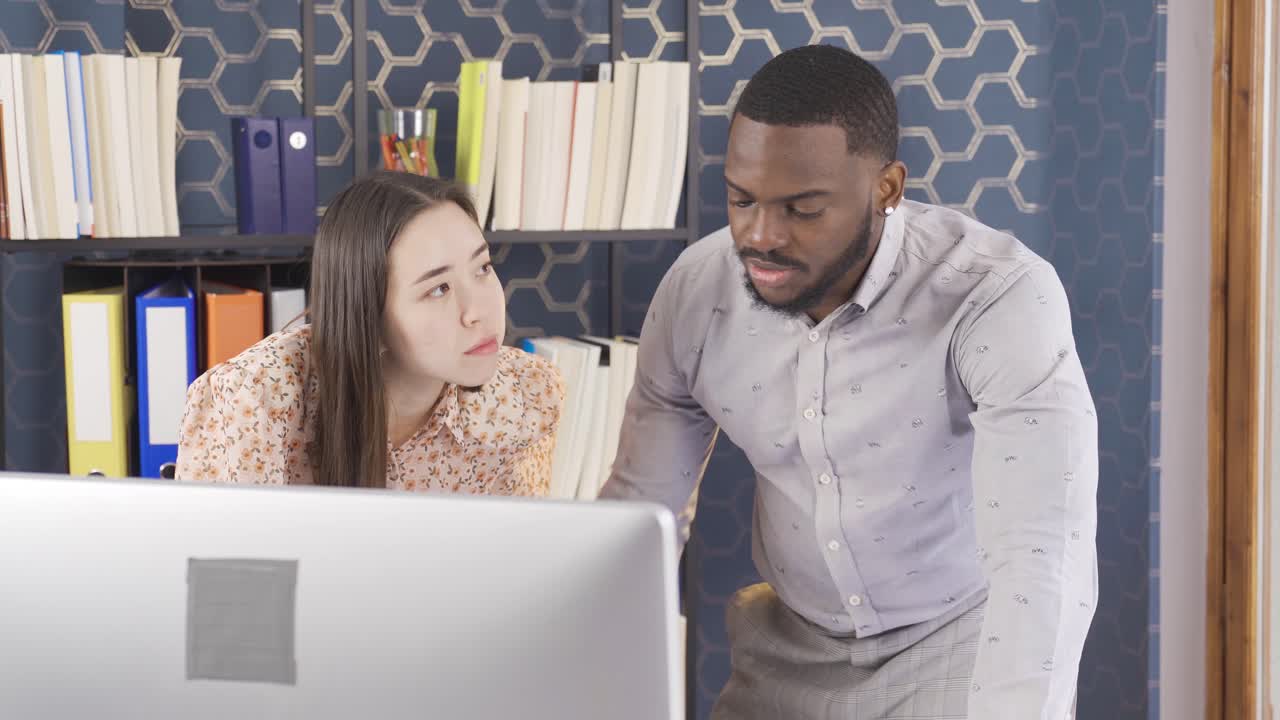 Asian woman and African man working together in the office.