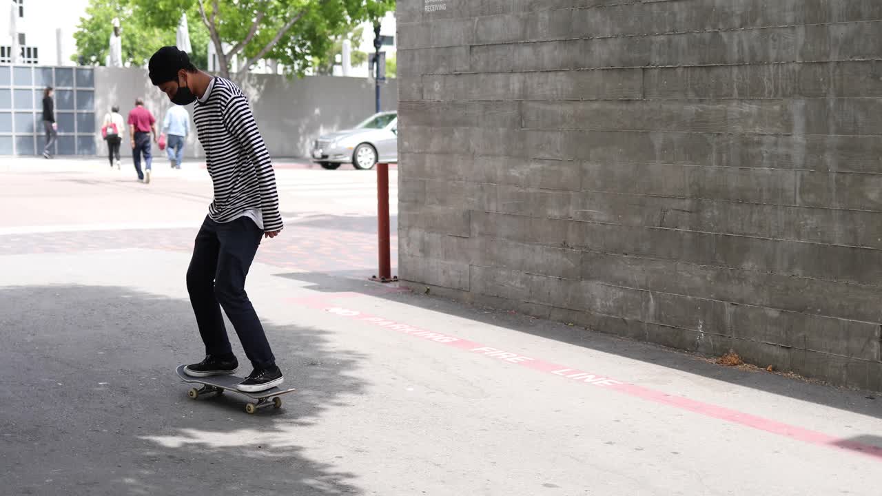 A man in a Covid mask does stunts on a skateboard during the coronavirus pandemic outbreak crisis