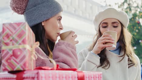 handheld view of two women drinking coffee on christmas market