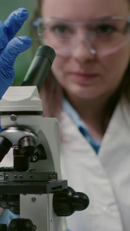 female scientist examining sample with microscope slide in laboratory