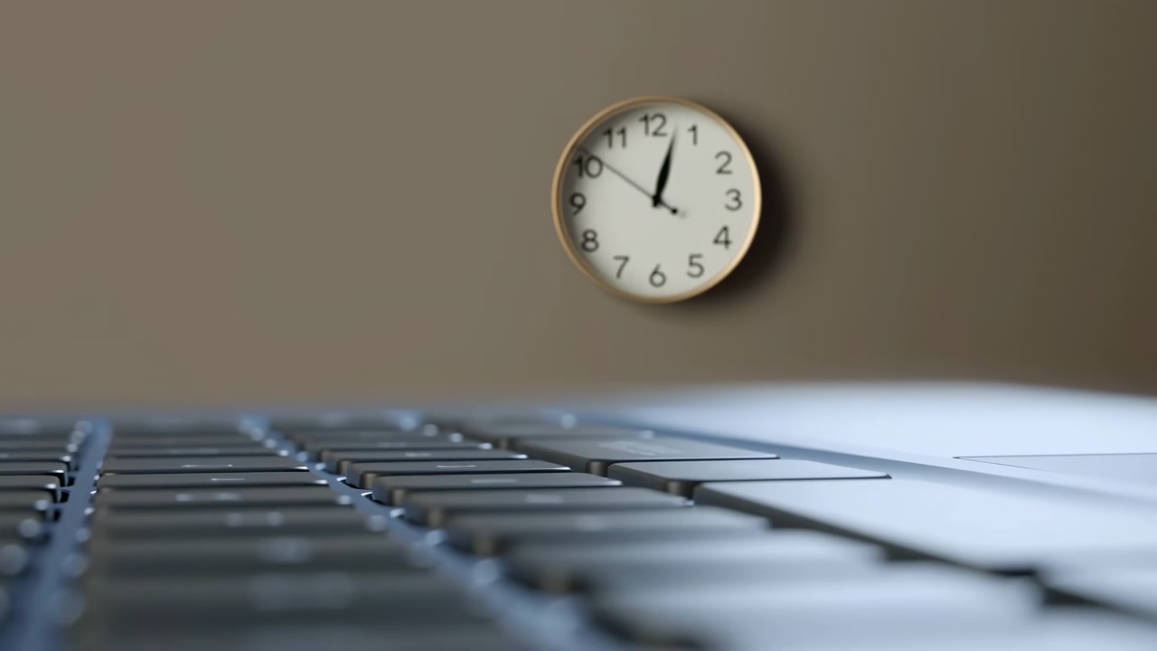 Ekstremt lav vinkel af et laptop-tastatur, der fylder forgrunden, med et rundt analogt vægur på en ensfarvet beige væg i øverste højre mellemgrund, der viser blødt skiftende fokus og en rolig kontoratmosfære.