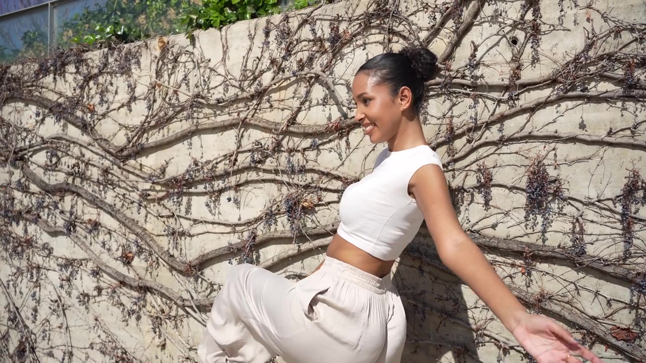 A stylish young woman posing outdoors against a beautifully textured wall backdrop