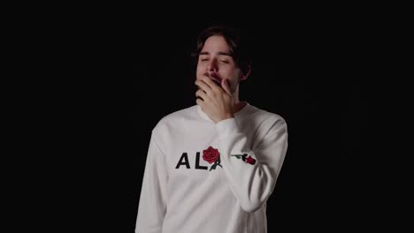 trendy young man yawning, tired gesture, wide, black background