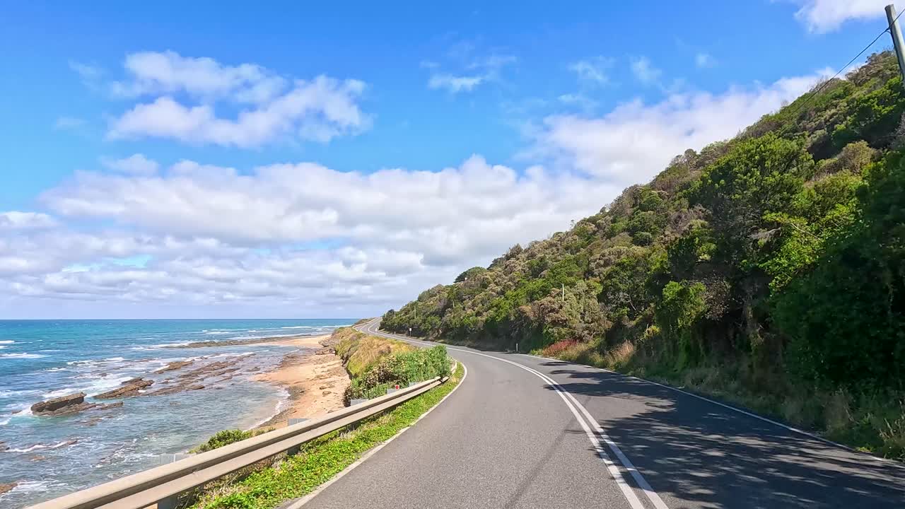 A serene drive along the Great Ocean Road with ocean views and lush greenery under clear blue skies