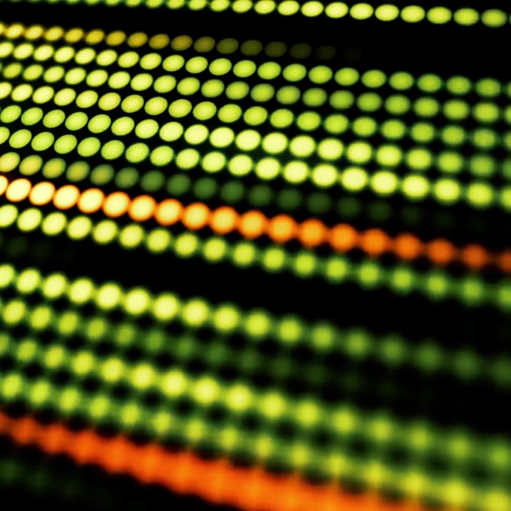 Dynamic Pattern of Glowing Green and Orange Dots on Black Background