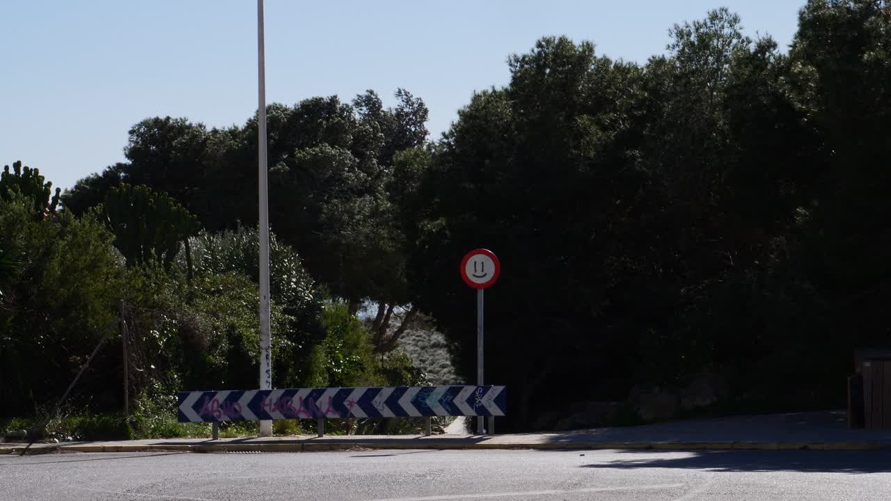 Trees swaying in the strong wind, and a prohibition sign with a happy face painted on it
