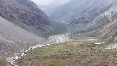 aerial drone shot following vehicles navigating sharp bends on a scenic mountain road.