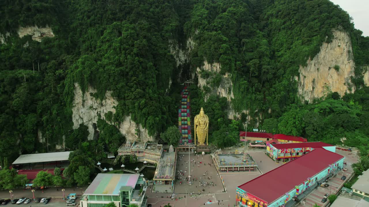 Aerial image of the famous Batu Caves, featuring the Cathedral Cave with the golden statue of Murugan and the colorful staircase, located near Kuala Lumpur, Malaysia.