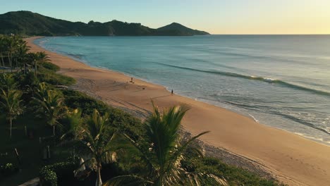 Aerial-view-paradise-beach-sunrise-with-white-sand-emerald-color-water-palm-trees-and-mountains