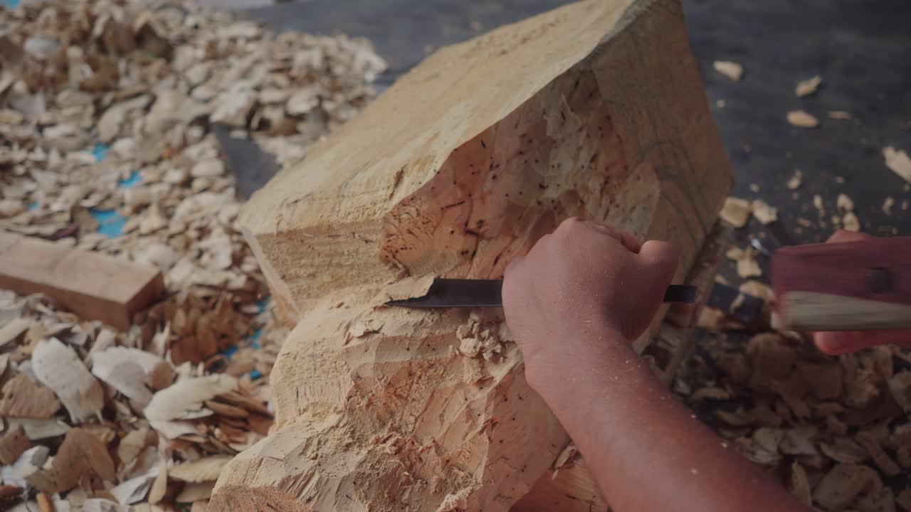 Handyman modeling a piece of wood with a chisel and hammer