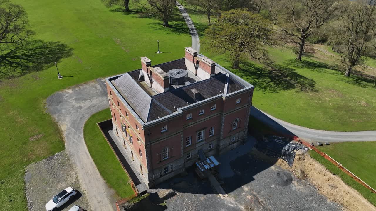 Bellamont House, County Cavan, Ireland, April 2023. Drone circling clockwise above historic grand architecture, green estate grounds surround, red brick design and rooftop aerial view.