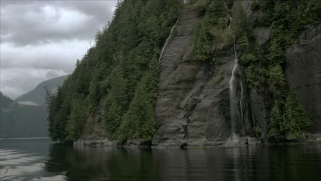 A-rocky-mountain,-in-an-Alaskan-fjord,-features-several-small-waterfalls-as-the-camera-rotates-around-the-mountain-itself