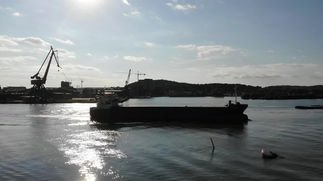 Oil tanker arriving at Port of Gothenburg with sun glitter on water, side shot
