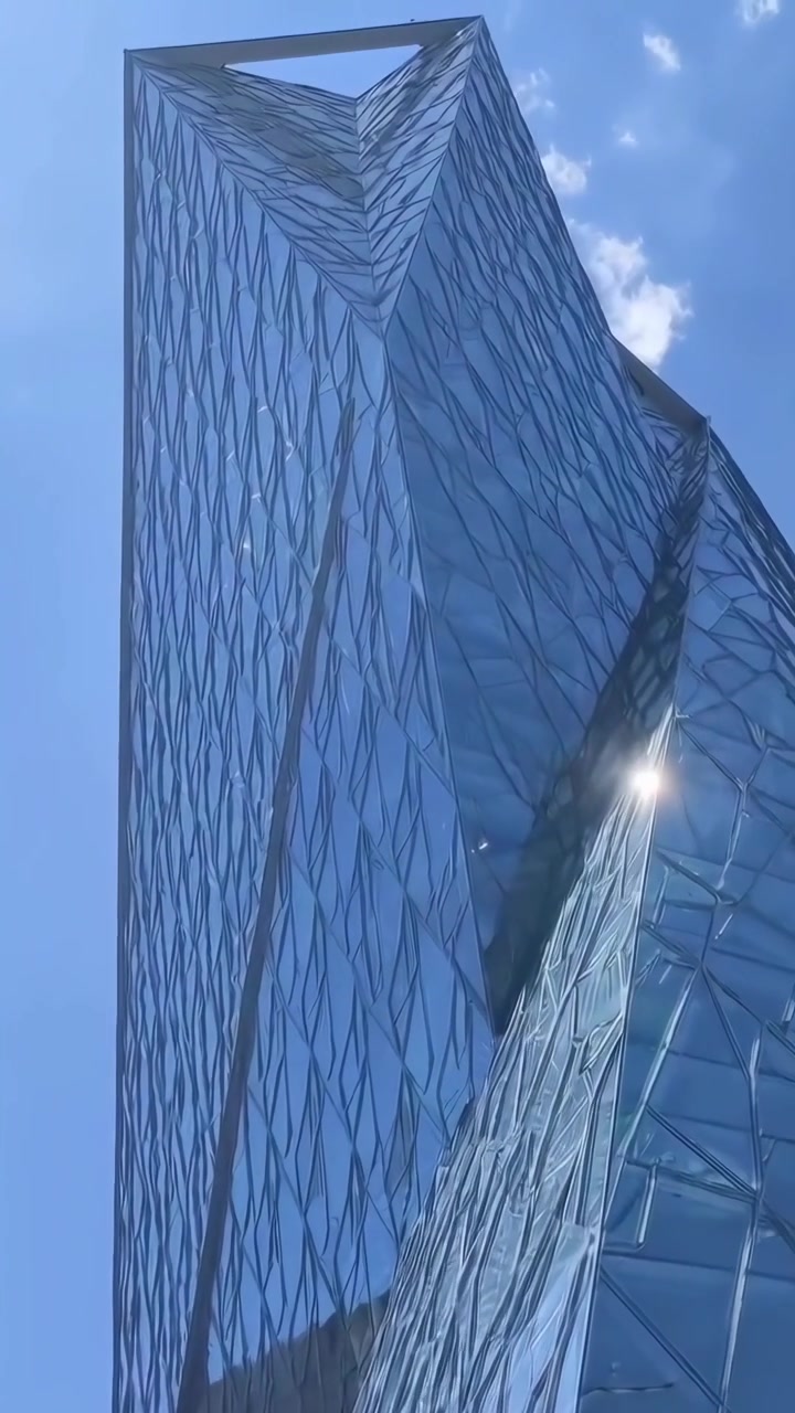 Vista en bajo ángulo de un moderno rascacielos de vidrio contra el cielo azul