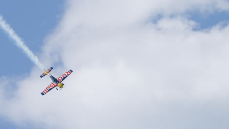 a colorful red bull racing aircraft performs a high speed controlled diving roll