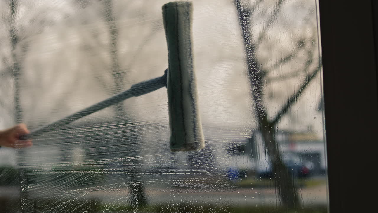 Woman manually washing house window with sprayer and mop outdoors. Safety at height, spring cleaning, cleaning services