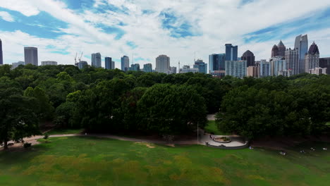 aerial slider of trees in city park, people relaxing in shadow