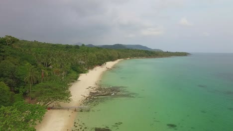 Aerial-drone-dolly-shot-of-a-beach-on-a-tropical-Thai-island-with-coconut-palms-and-jungle-and-resort-and-clear-ocean-in-Koh-Kood,-Thailand