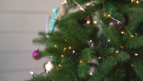 Vista-De-Cerca-De-La-Mano-De-La-Mujer-Colgando-Un-Corazón-Rojo-De-Madera-En-El-árbol-De-Navidad