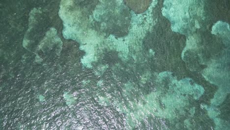 Top-down-aerial-view-of-green-ocean-water-over-reef-and-sand-bar-by-reef