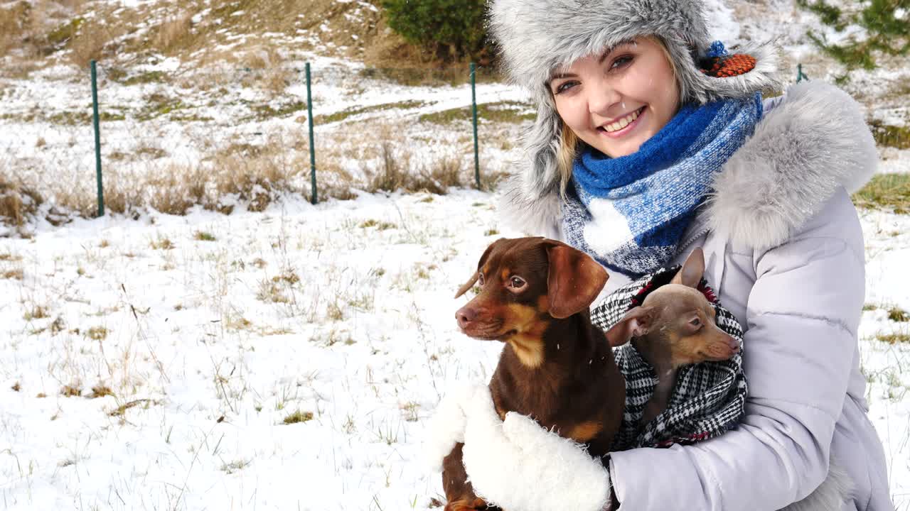 여자 는 겨울 밖 에서 작은 개 들 과 함께 놀고 있다