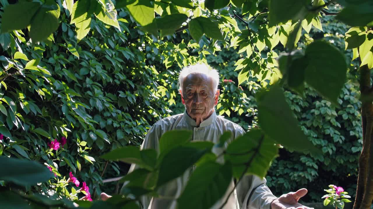 An elderly man stands amidst lush greenery, captured from a low angle