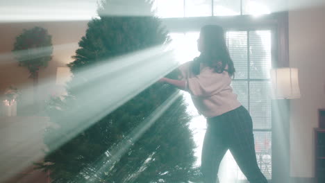 woman decorating christmas tree with atmospheric light rays