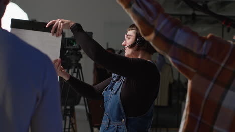 female assistant on film set in studio using clapperboard or slate on movie or video as actors start scene 5