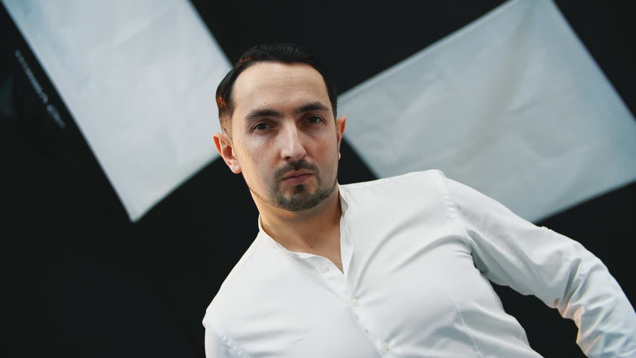 진지하고 집중적인 젊은 남자가 카메라를 바라보고, 포즈를 취하고, 그의 손은 아보입니다.