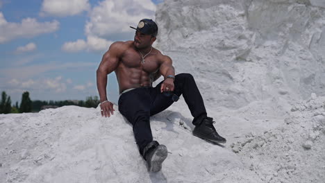 Bodybuilder with naked torso outdoor. Handsome athlete man showing muscles on the rocky mountain