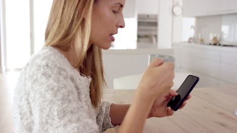 Mujer-Real-Usando-Teléfono-Móvil-En-Casa-Tomando-Café-Disfrutando-De-Un-Estilo-De-Vida-Relajante