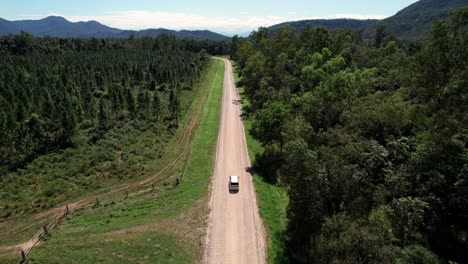 Drohnenaufnahme-Eines-Wohnmobils,-Das-An-Einem-Sonnigen-Tag-Auf-Einer-Schotterstraße-In-Queensland-Mit-Bergen-Im-Hintergrund-Fährt