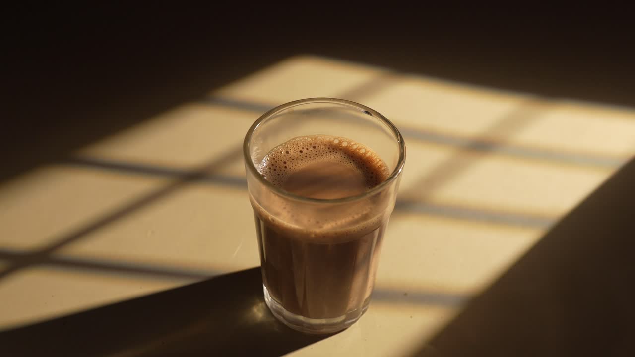 Chai indiano servito in tazze di vetro, preparato in una teiera di metallo con masala aromatici