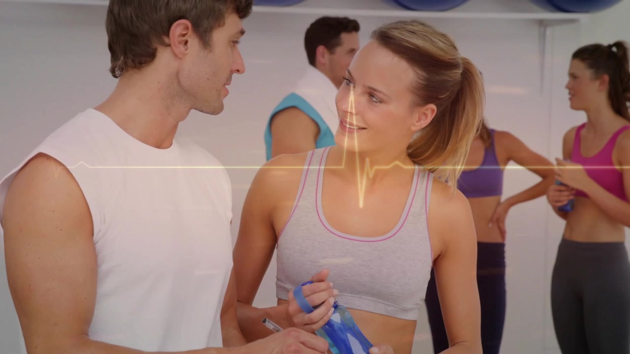 Verticale video: Coach wijst naar klembord, vrouw leunt met blauwe fles, ECG-verbinding met fitnessles
