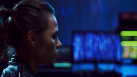 close up of the beautiful young female hacker looking at the screen of computer while working at night in the dark