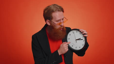 joven barbudo mostrando el tiempo en el reloj, ok, pulgar arriba, aprobar, señalando con el dedo a la cámara