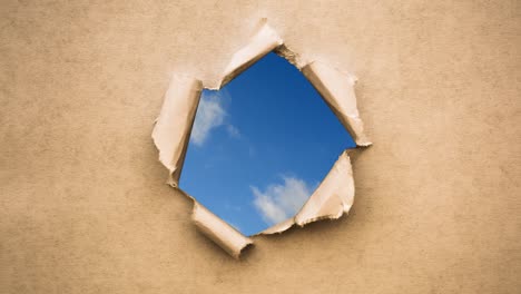 creative 4k time laps video of fast moving clouds in the blue sky that are visible through a circle hole with torn edges in old retro grunge vintage paper.