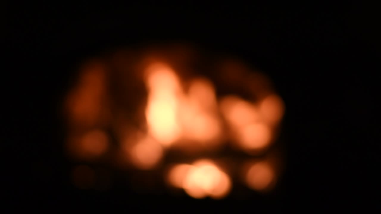 Bokeh campfire flame glowing in night darkness