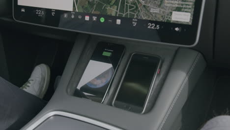 Tesla-driver-puts-his-smarthone-onto-center-console-next-to-another-smartphone-for-wireless-charging