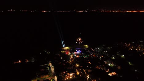 Vista-Aérea-De-La-Ciudad-Por-La-Noche-Con-Fuegos-Artificiales-En-Cámara-Lenta-Iluminando-El-Cielo