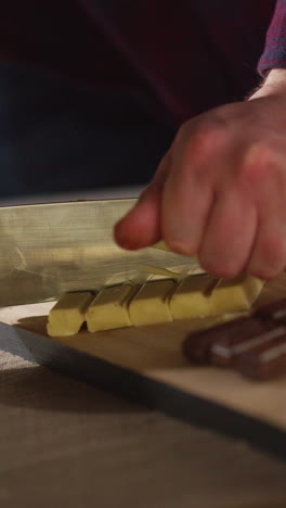 vertical video of person cutting bars of milk plain and white chocolate into smaller pieces with knife 2