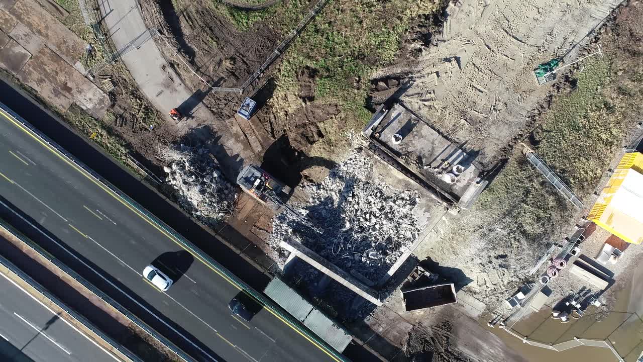 disparo de drones de escombros de un sitio de construcción al lado de una autopista donde los coches y camiones están conduciendo