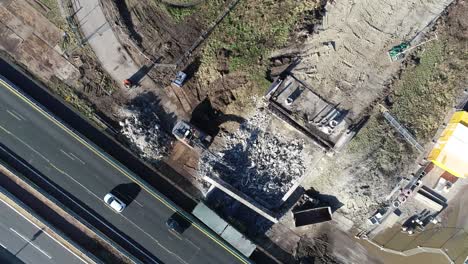 drone shot of rubble from a construction site next of a highway where cars and trucks are driving