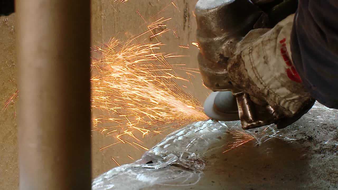 Close-up of a worker grinding metal with sparks flying