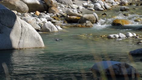 Tracking-shot-of-drone-filming-flying-very-low-above-stream-river-water