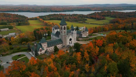 Toma-Aérea-Sobre-La-Abadía-De-Saint-Benoit-Du-Lac-Cerca-De-Magog-En-La-Provincia-De-Quebec-Con-El-Lago-Memphremagog-Al-Fondo-Durante-El-Otoño,-Temporada-De-Otoño,-Canadá