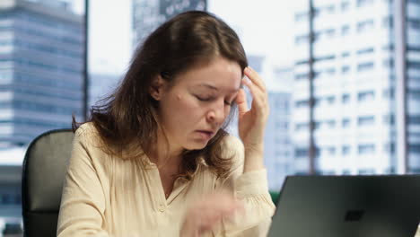 exhausted overwhelmed businesswoman with a headache trying to meet deadline