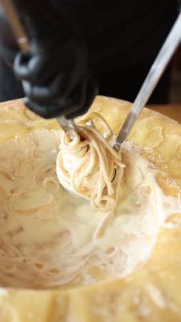 chef serving creamy pasta in a parmesan wheel