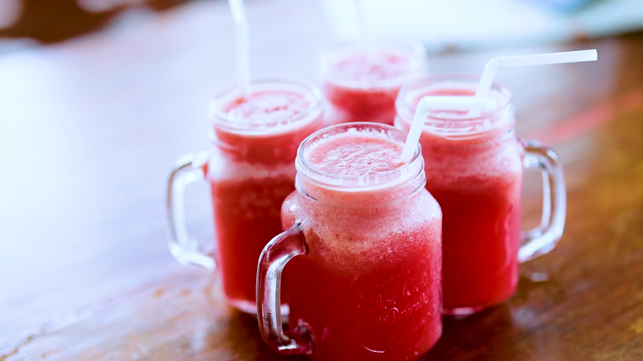 Hands reaching for watermelon juice in glass jars